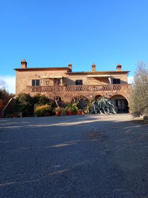 Una semplice casa di campagna immersa nel verde, circondata da un giardino e sotto un cielo chiaro.