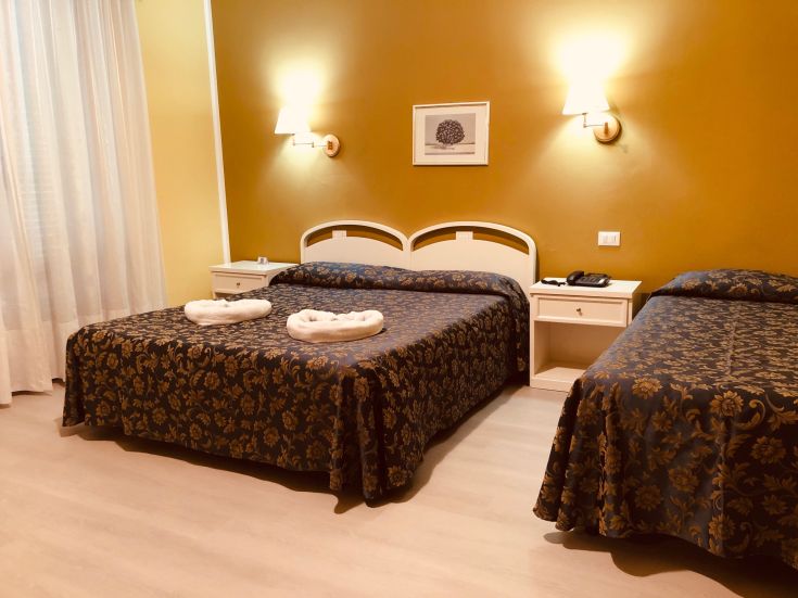 Chambre simple avec lits doubles et simples, meublée dans des tons chauds.