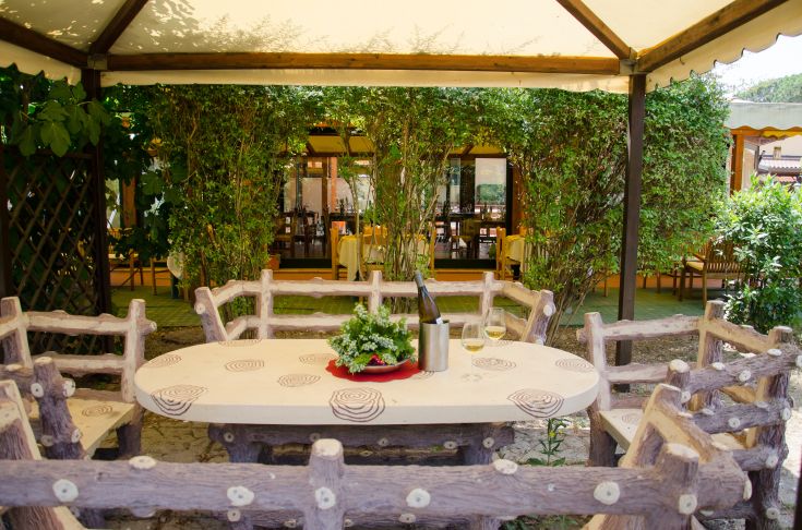 Une table en plein air entourée de plantes, parfaite pour manger dehors dans un cadre paisible.