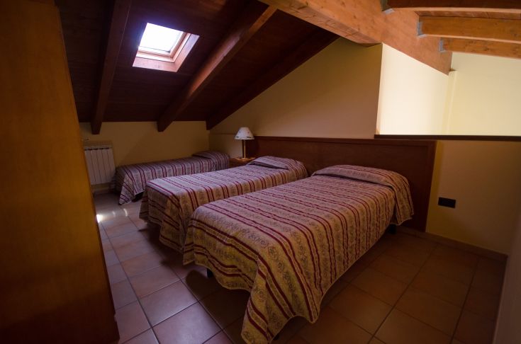 Chambre simple avec des lits simples et un plafond en bois, idéale pour un séjour calme.