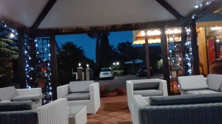 Une zone extérieure avec des canapés blancs, éclairée par des lumières tamisées, créant une atmosphère sereine pour la soirée.