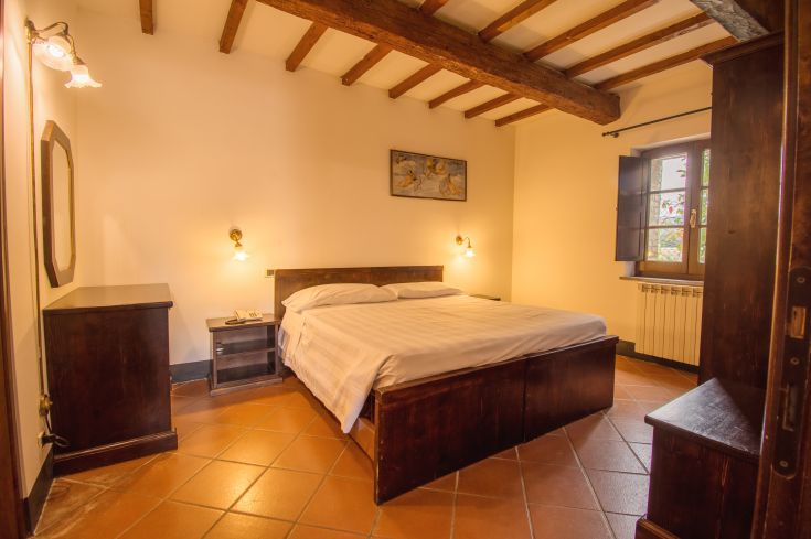 A cozy room with wooden beds and simple furnishings. A window allows natural light to enter.