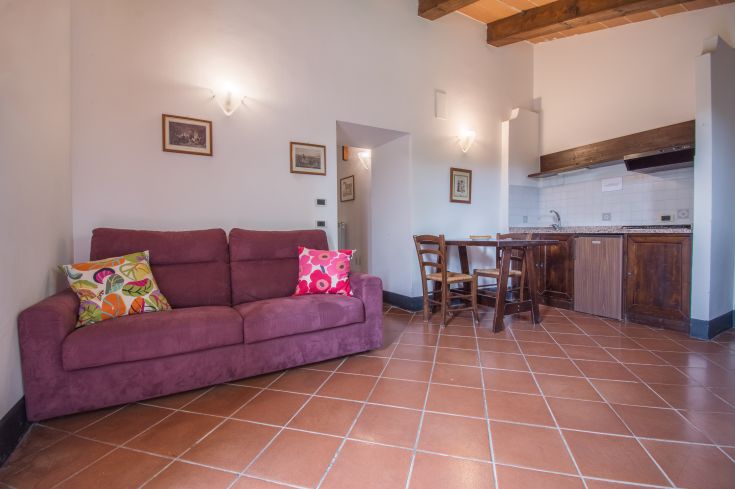 A rustic living room in an old barn, furnished with a cozy sofa and a table for relaxation and sharing.