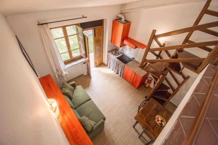 Simple apartment with functional kitchen, bright living room, and staircase leading to the upper floor.