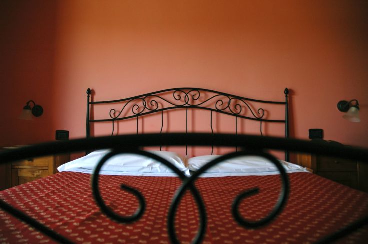 Cozy bedroom with a metal headboard, intimate atmosphere, and orange wall. Bright and comfortable space.