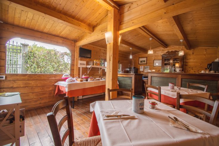 Interior of a wooden restaurant with rustic details, overlooking a green area.