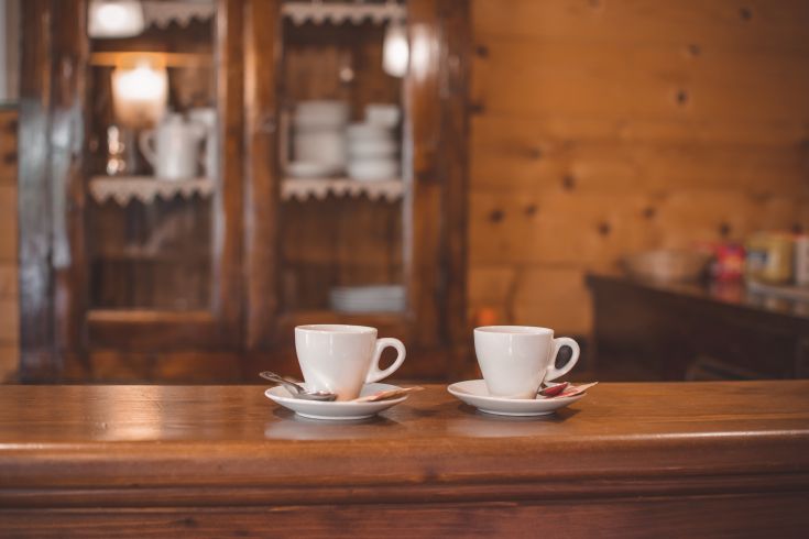 Two steaming cups of coffee on a wooden table in a warm and inviting setting.