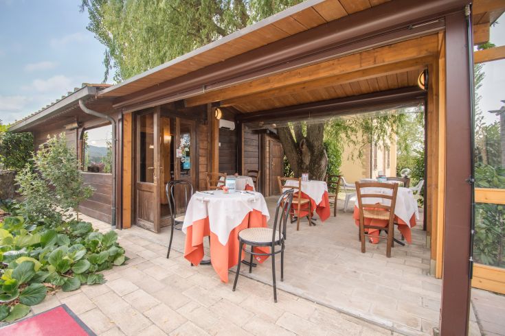 An outdoor restaurant surrounded by plants, featuring well-arranged tables in a relaxed atmosphere.
