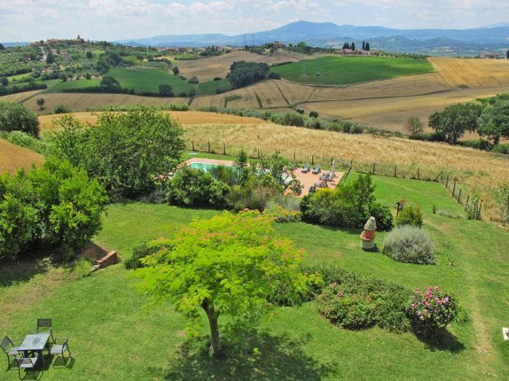 Ein ruhiger Bauernhof auf einem Hügel, umgeben von Grün, mit Blick auf Felder und einen See.