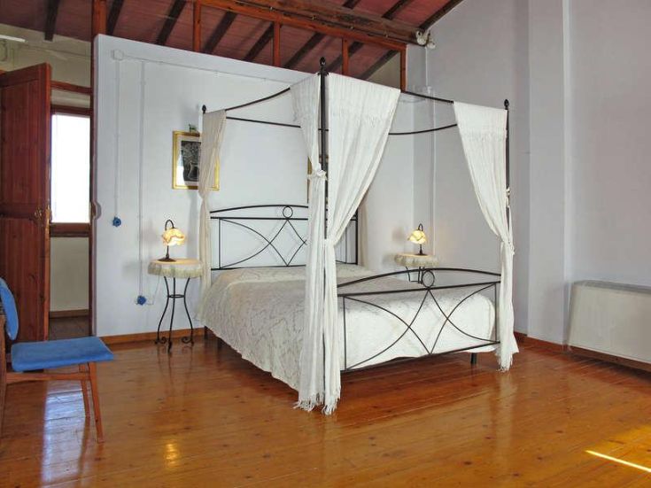 Einfache Schlafzimmer mit einem Himmelbett und Holzdekorationen, ideal für ruhige Momente.