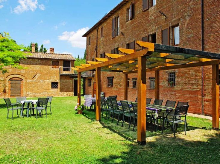 Entspannender Garten mit Tischen und Pergola, gelegen in einem alten Gebäude zwischen der Toskana und Umbrien.