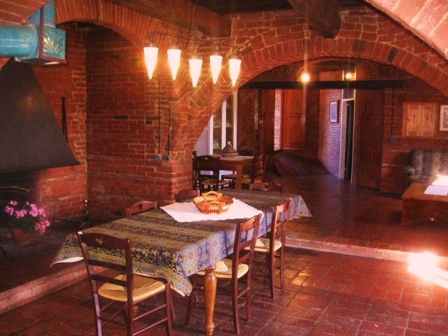 Gemütlicher Speiseraum eines Agriturismo mit einem rustikalen Tisch und Sichtziegelwänden.