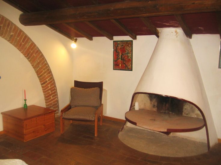 Ein schlichtes Wohnzimmer mit Kamin und Holzmöbeln in einem historischen Gebäude.