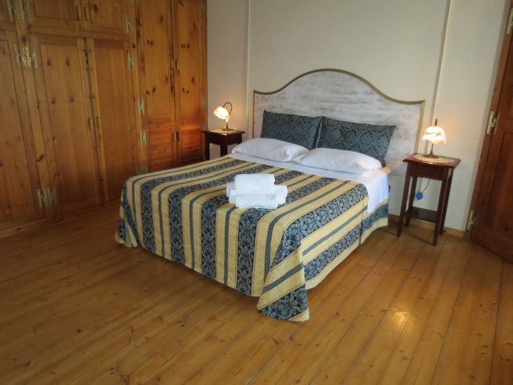 Einfache Schlafzimmer mit einem Doppelbett, Holzmöbeln und ruhiger Atmosphäre.