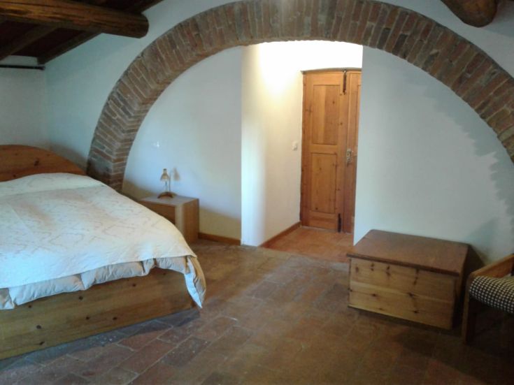 Gemütliches Interieur mit einem Doppelbett und Holzmöbeln, schafft eine ruhige und rustikale Atmosphäre.