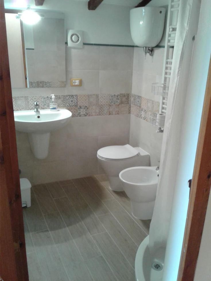 Ein gut beleuchtetes, modernes Badezimmer mit schlichten Fliesen und praktischen Möbeln.