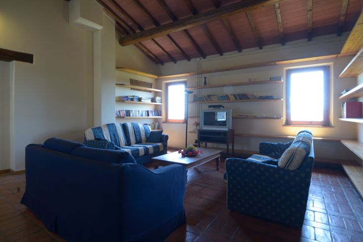 Wohnzimmer mit blauen Sofas, Fernseher und Bücherregal. Ein gemütlicher und informeller Ort zum Entspannen.