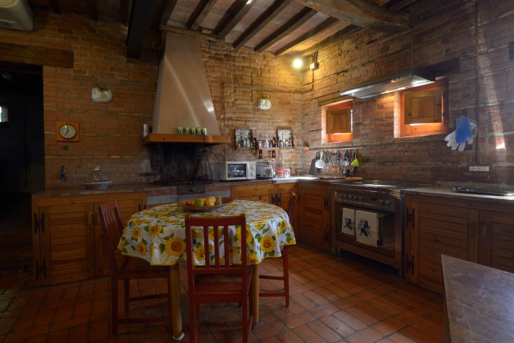 Einfache Kücheneinrichtung mit sichtbaren Backsteinelementen und warmen, einladenden Möbeln.