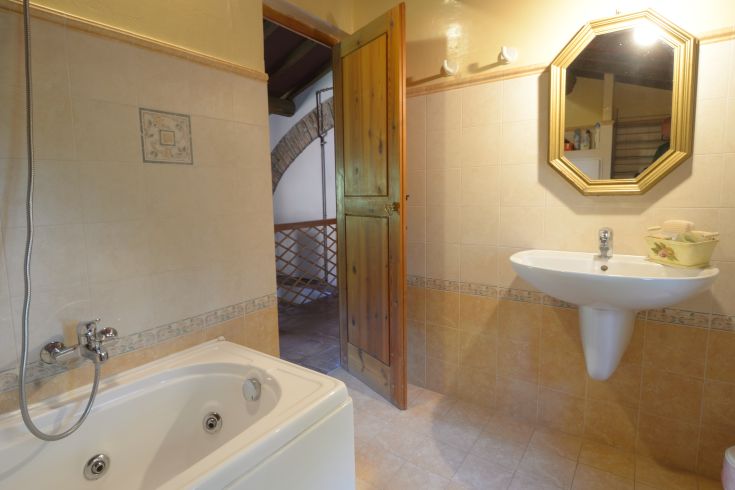 Ein schlichtes Badezimmer mit Badewanne und Waschbecken, dekoriert mit schlichten Keramikdetails.