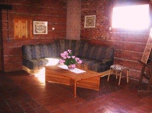 Ein gemütlicher Wohnbereich mit einem Sofa und einem Couchtisch, beleuchtet von einem Fenster, mit einer warmen und informellen Atmosphäre.