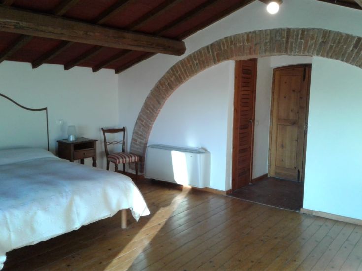 Helle Zimmer mit sichtbarem Holzbalkendecke, schlichtem und funktionellem Mobiliar.