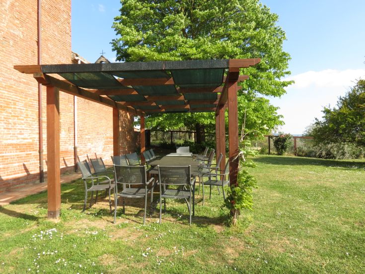 Ein Außenbereich mit Tischen und Stühlen, umgeben von Grün, der eine seriöse Atmosphäre schafft.