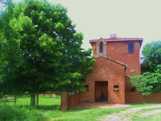 Ein historisches Gebäude, umgeben von Grünflächen, Hügeln und Olivenbäumen, schafft eine ruhige Atmosphäre.