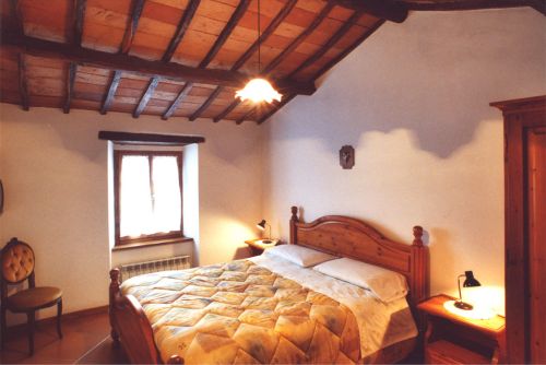 Cozy double bedroom with wooden ceiling and soft lighting.