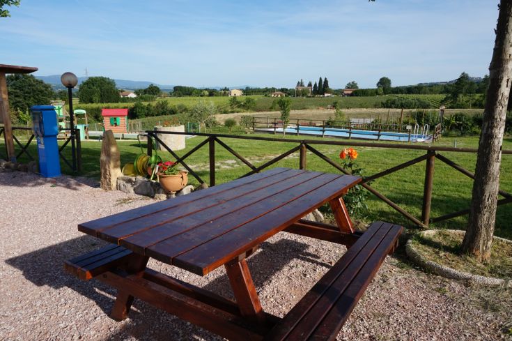 In un ambiente di colline e uliveti, un tavolo di legno accoglie momenti di relax nella natura.