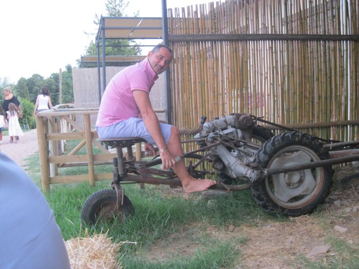 Un uomo sorridente su un vecchio trattore circondato da un paesaggio rurale.