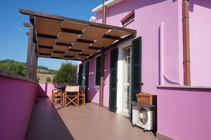 Balcone di un agriturismo con colori vivaci, situato nella campagna umbra, che si affaccia su colline verdeggianti.