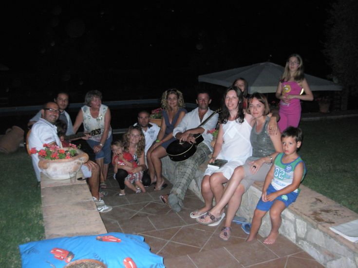 Incontro tra amici e familiari in un ambiente esterno, caratterizzato da una piacevole atmosfera e musica dal vivo.