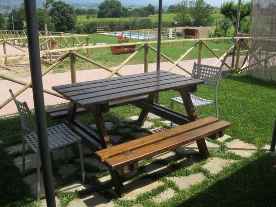 Un tavolo in legno circondato da sedie, situato in un ambiente rurale e sereno.