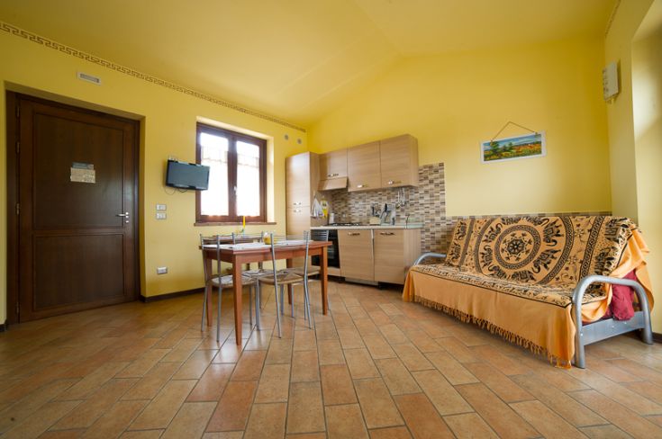 Soggiorno giallo con cucina ben attrezzata e area pranzo, ideale per momenti di relax.