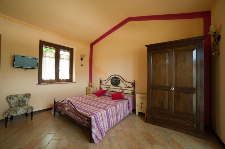 Stanza confortevole con letto matrimoniale, armadio di legno e luce naturale. Ideale per un soggiorno tranquillo.