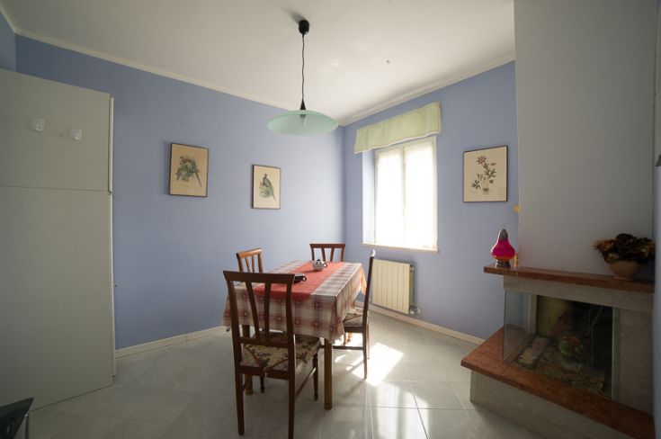 Ambiente armonioso con tavolo e sedie, arricchito da semplici decorazioni floreali, perfetto per incontri tra amici.