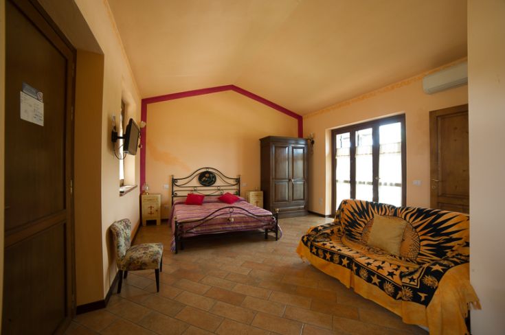 Camera semplice ed accogliente con letti e una poltrona, immersa nella tranquillità della natura.