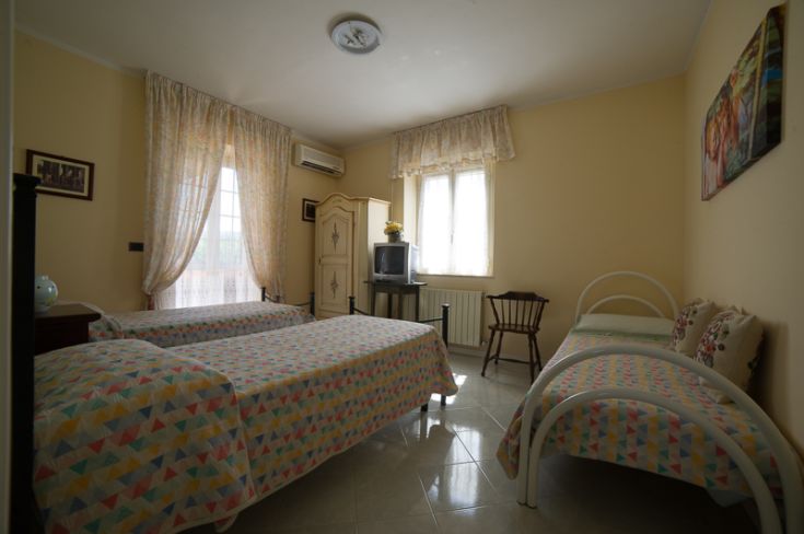 Camera spaziosa e ben illuminata, perfetta per momenti di relax in famiglia, dotata di letti singoli e TV.