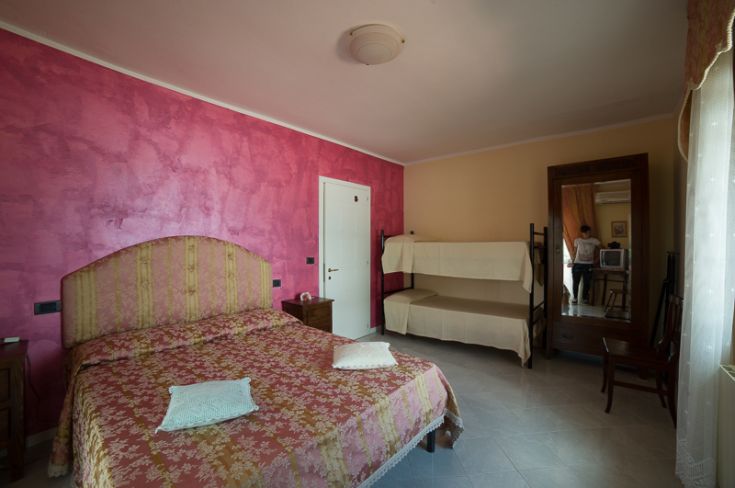 Camera confortevole con pareti rosa e letti a castello, affacciata su un ambiente tranquillo.