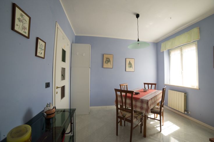 Cucina spaziosa con tavolo per sei persone e piante decorative, creano un'atmosfera rilassante.