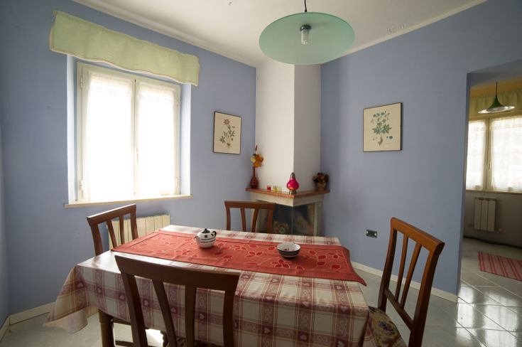 Spaziosa sala da pranzo con un tavolo centrale e decorazioni sobrie, in un'atmosfera tranquilla.