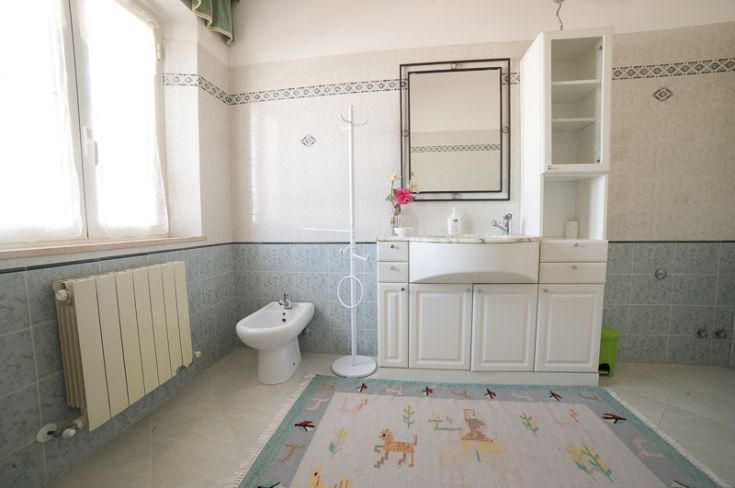 Bagno ampio e ben curato, con sanitari contemporanei e un grande specchio, perfetto per momenti di relax.