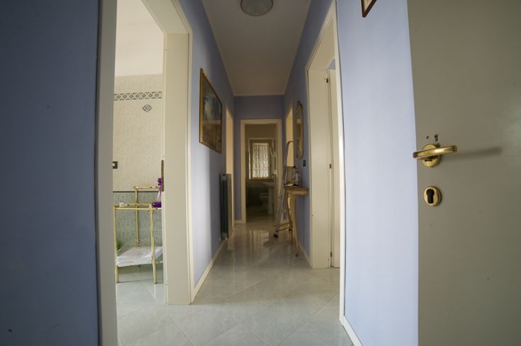 Un lungo corridoio con pareti blu che porta a diverse stanze della casa.