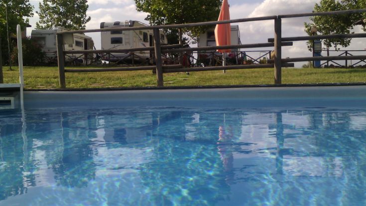 Una piscina pulita, circondata da colline verdi e aree per camper, perfetta per un momento di relax nella natura.