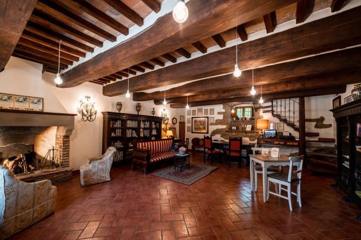 Spazio tranquillo con camino, travi a vista e arredi semplici per momenti di riposo.