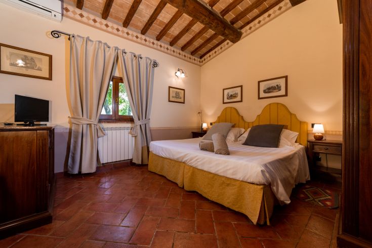 Camera luminosa e confortevole con finestre affacciate su un'area verde, letti pratici e arredi in stile rustico.