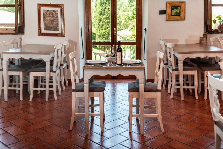 Un ristorante con tavoli e sedie in legno, arredato in modo semplice e con dettagli floreali.
