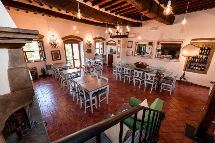 Spazio ristorante luminoso con tavoli bianchi e lampade che creano un'atmosfera piacevole.