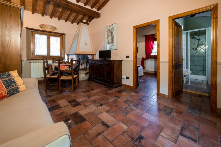 Un soggiorno accogliente con pavimenti in cotto e angolo cottura, affacciato sulla campagna.