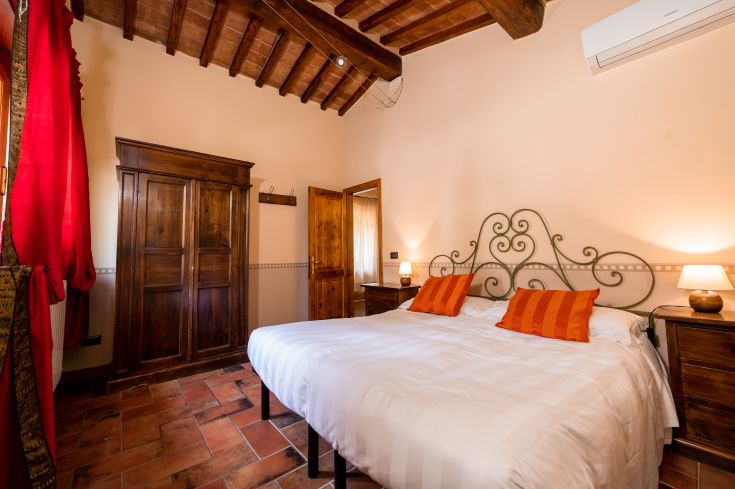 Camera semplice con letto matrimoniale, tonalità calde e un'atmosfera rustica.